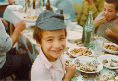 Repas de fête à une cérémonie de circoncision portrait d'un enfant souriant mangeant des fèves